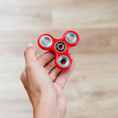 Fidget fırıldağı. Kırmızı el çevirici, titrek el oyuncağı çocuğun elinde dönüyor. Stres atmak. Stres önleyici ve rahatlatıcı. İlgi çekici çocuk konsepti.