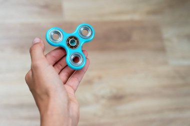 Fidget fırıldağı. Mavi el hareketi, titrek el oyuncağı çocuğun elinde dönüyor. Stres atmak. Stres önleyici ve rahatlatıcı. İlgi çekici çocuk konsepti. Metin için boş alan