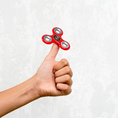 Fidget fırıldağı. Kırmızı el çevirici, titrek el oyuncağı çocuğun elinde dönüyor. Stres atmak. Stres önleyici ve rahatlatıcı. İlgi çekici çocuk konsepti.