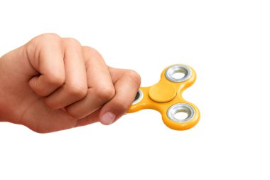 Sarı el çabukluğu. Çocuk elinde popüler bir oyuncak fırıldağı oynuyor. Stres atmak. Stres önleyici ve rahatlatıcı. İlgi çekici çocuk konsepti.