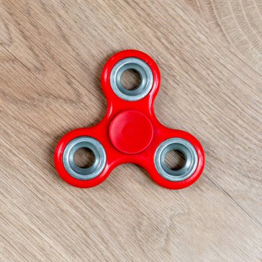 Fidget fırıldağı. Ahşap arka planda kırmızı el çevirici
