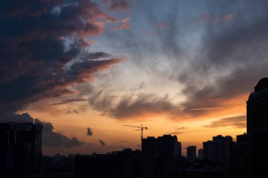 Şehir manzarasında gün batımında bulutlarla dolu renkli dramatik bir gökyüzü.
