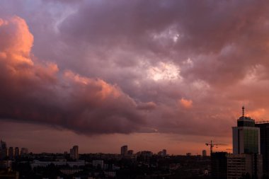 Şehir manzarasında gün batımında bulutlarla dolu renkli dramatik bir gökyüzü.