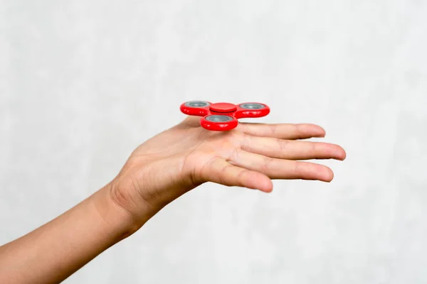 Red hand spinner. Boy playing a popular toy fidget spinner in his hand. Stress relief. Anti stress and relaxation adhd attention fad boy concept