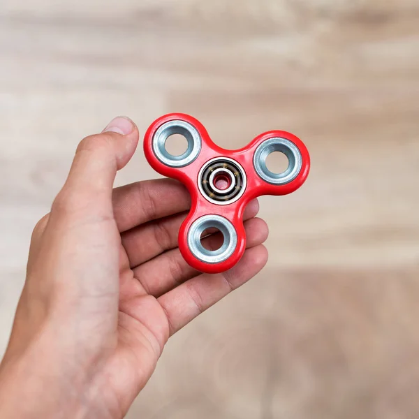 Fidget spinner. Red hand spinner, fidgeting hand toy rotating on child's hand. Stress relief. Anti stress and relaxation adhd attention fad boy concept