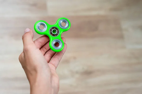 Fidget spinner. Green hand spinner, fidgeting hand toy rotating on child\'s hand. Stress relief. Anti stress and relaxation adhd attention fad boy concept. Free space for text