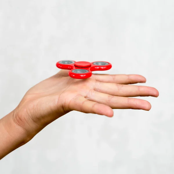 Red hand spinner. Boy playing a popular toy fidget spinner in his hand. Stress relief. Anti stress and relaxation adhd attention fad boy concept