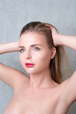 Çıplak ve zarif bir bayanın moda stüdyo portresi. Gri arka planda mükemmel ciltli sarışın kadın.