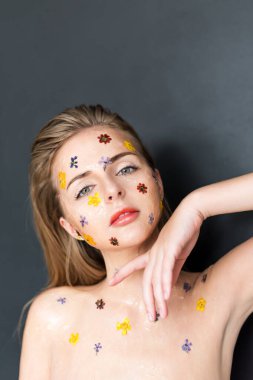 Yüzünde şeffaf jel ve çiçeklerle çıplak zarif bir kadının moda stüdyosu portresi. Vücut ve cilt bakımı, parfüm, kozmetik konsept