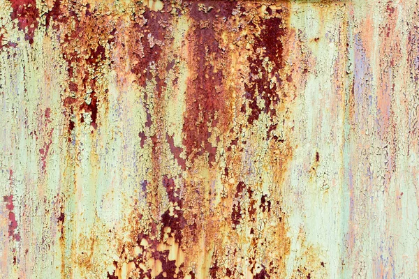 Rusty painted metal texture. Old iron background painted in yellow with rust. Weathered metal wall surface with cracked paint