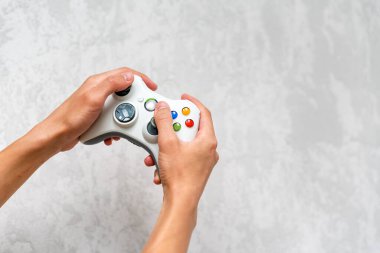 Gri beton zeminde el ele tutuşmalar. Evde video oyunu oynayan kontrollü bir adam. Boş zaman ve eğlence. Oyuncuların elinde bilgisayar oyunu konsolu kontrolörü. Metin için boşluğu kopyala.