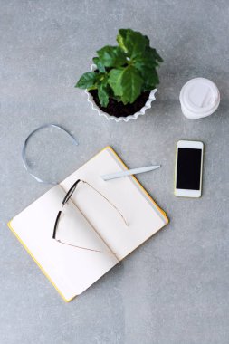 Ofis masasında defter planlayıcısı, akıllı telefon, bardaklar, kahve ağacı ve kahve fincanı. Kopyalama alanı olan üst görünüm