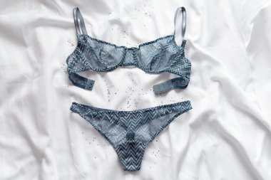 Beyaz çarşaf üzerinde göz kamaştırıcı, seksi dantel iç çamaşırları. Kadın aksesuarları. Alışveriş ve moda konsepti