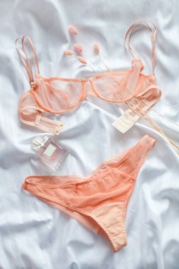 Kadın aksesuarları, güzellik ürünleri, beyaz çarşaflı parfümlü göz kamaştırıcı seksi dantel iç çamaşırları. Alışveriş ve moda konsepti