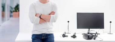 Bilgisayarın yanında duran dijital tasarımcı ve beyaz masada duran sanal gerçeklik kulaklığı