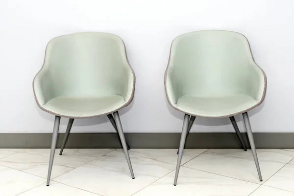 眼前的现代 简朴的椅子靠着灰色的墙壁 在一个简约风格的候车室内部 医生办公室候诊室里的椅子 上面有文字复制的地方 — 图库照片