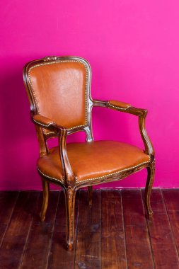 Koltuğu, pembe duvarı ve ahşap zemini olan minimalist bir iç mekan. Metin için alanı kopyala