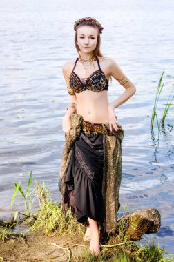 Genç kadın kabile Amerikan stili dansçı. Dans eden, kumsalda poz veren, göbek dansı kostümü giyen bir kız. Etnik dans. Göbek dansı. Kabile dansı