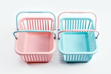 Renkli plastik alışveriş sepetleri. Gri arka planda boş pembe ve mavi süpermarket sepetleri. Yaratıcı minimalist tasarım, online alışveriş. Kara Cuma ve Satış Konsepti