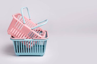 Renkli plastik alışveriş sepetleri. Gri arka planda boş pembe ve mavi süpermarket sepetleri. Yaratıcı minimalist tasarım, online alışveriş. Kara Cuma ve satış konsepti, metin için boş alan