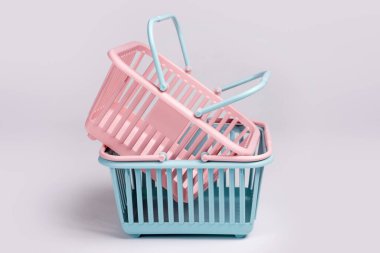 Renkli plastik alışveriş sepetleri. Gri arka planda boş pembe ve mavi süpermarket sepetleri. Yaratıcı minimalist tasarım, online alışveriş. Kara Cuma ve Satış Konsepti