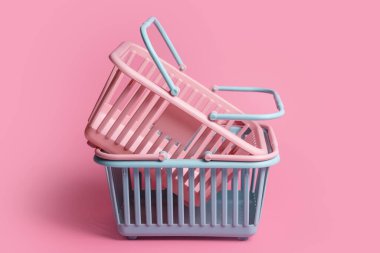 Renkli plastik alışveriş sepetleri. Pembe pastel arka planda boş pembe ve mavi süpermarket sepetleri. Yaratıcı minimalist tasarım, online alışveriş. Kara Cuma, indirim, reklam ve satış konsepti
