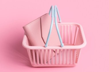 Deri cüzdanlı renkli plastik alışveriş sepetleri. Pembe pastel arka planda boş pembe ve mavi süpermarket sepeti. Yaratıcı tasarım, alışveriş, kara Cuma, indirim, reklam, satış konsepti