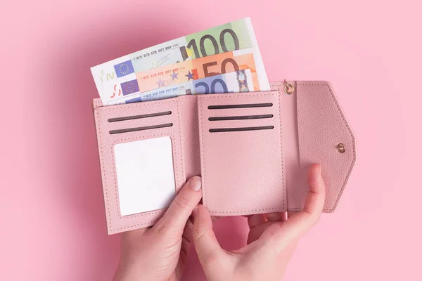 Hands holding wallet. Pink leather wallet with euro money in female hands. Closeup on a woman's hands taking European bank notes out of purse and counting. Concept of money, finances, shopping, cash