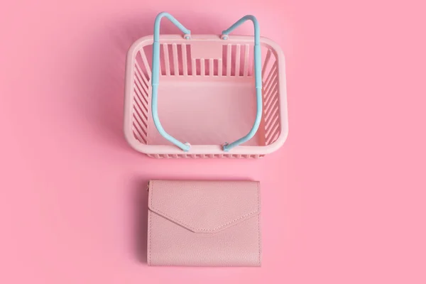 Colorful plastic shopping baskets with leather wallet. Empty pink and blue supermarket basket on pink pastel background. Creative design, shopping, black friday, discount, advertising, sale concept