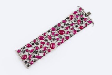 Fashion bracelet with diamonds and sapphire natural gem stones on gray background. Pink and black precious stones in luxury diamond jewelry bracelet.