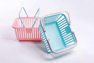 Renkli plastik alışveriş sepetleri. Gri arka planda boş pembe ve mavi süpermarket sepetleri. Yaratıcı minimalist tasarım, online alışveriş. Kara Cuma ve satış konsepti, metin için boş alan