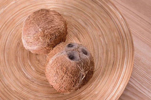 Целые кокосы на тарелке на натуральном деревянном фоне. — стоковое фото