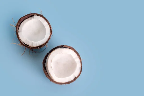 ライトブルーの背景にココナッツの半分にクラック 生ココナッツの半分 — ストック写真