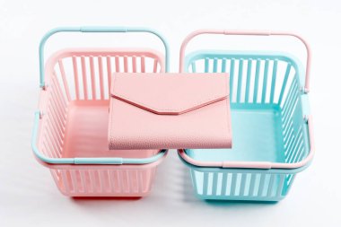 Deri cüzdanlı renkli plastik alışveriş sepetleri. Açık arkaplanda boş pembe ve mavi süpermarket sepetleri. Yaratıcı tasarım, alışveriş, kara Cuma, indirim, reklam, satış konsepti