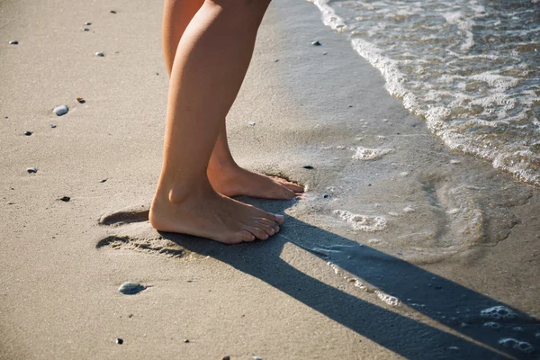 Pieds de la fille marchant dans les vagues de la mer — Photo