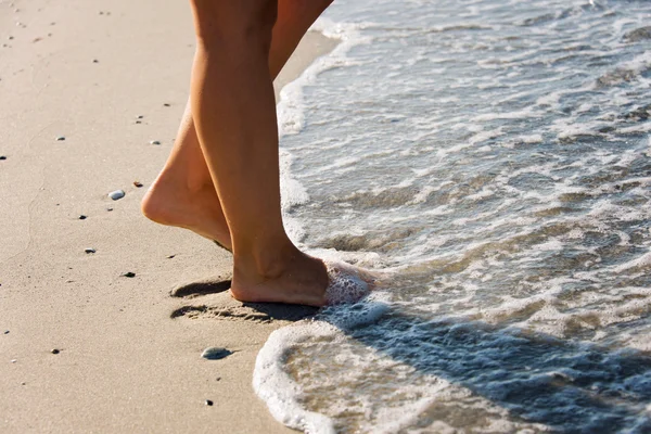 Pieds de la fille marchant dans les vagues de la mer — Photo