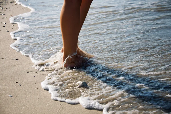 Pés da menina que anda em ondas do mar — Fotografia de Stock