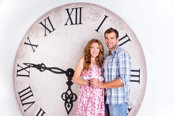 Happy Pregnant Couple on white background with giant clock — Stock Photo, Image