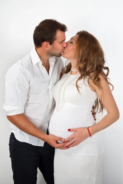 Щаслива вагітна пара одягнена в білий поцілунок на білому тлі — стокове фото