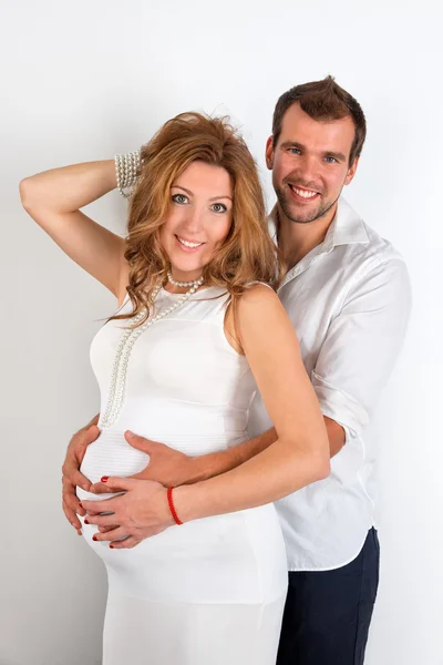 Happy Pregnant Couple dressed in white on white background — Stock Photo, Image