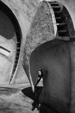 Fütürist binanın arka planında uzun siyah eşarp takan moda sarışın kız..