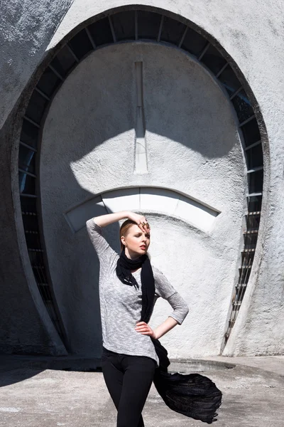 Ung mode blond flicka bär lång svart halsduk på bakgrunden av den futuristiska byggnaden. — Stockfoto