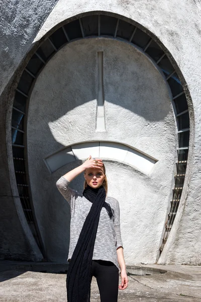 Ung mode blond flicka bär lång svart halsduk på bakgrunden av den futuristiska byggnaden. — Stockfoto