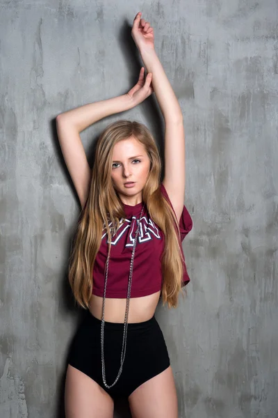 Sexy mujer rubia joven en lencería de lujo negro y camiseta deportiva posando contra la pared gris grumosa. Pasión y deseo posan. Mujer atractiva con cadena larga y preciosa . — Foto de Stock