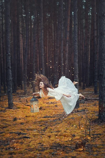 Mujer levitante en el bosque con una linterna en la mano . — Foto de Stock