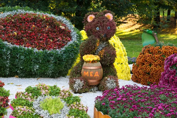 Flower beds in a shape of bear eating honey among different fruits with colorful chrysanthemums. Parkland in Kiev, Ukraine. — Stock Photo, Image