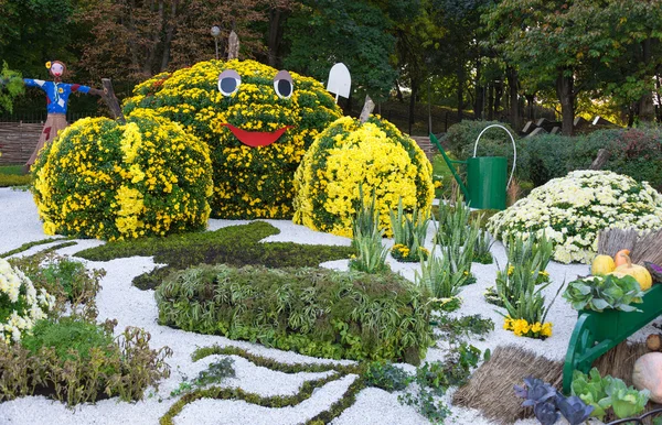 Moestuin, bewaakt door een vogelverschrikker. Grote cijfers gemaakt van bloemen in de vorm van groenten met kleurrijke chrysanten. Parkland in Kiev, Oekraïne. — Stockfoto