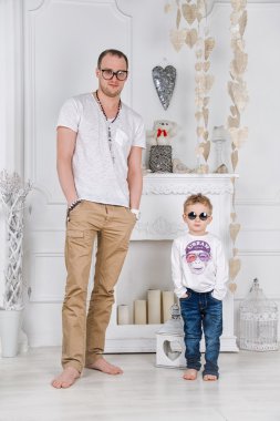 Baba ve oğul bir şömine ile beyaz oturma odasında. Erkek moda.