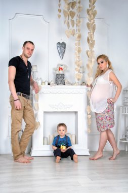 Bir şömine ile beyaz oturma odasında bir çocuk ile mutlu bir aile.