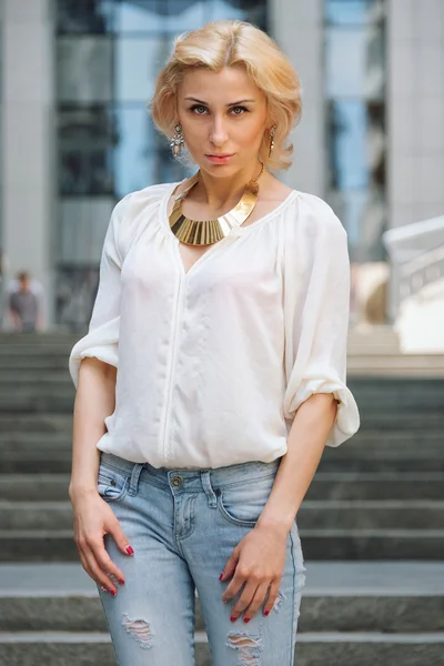 Moda de verano al aire libre impresionante retrato en bastante joven rubia sexy mujer vestida con una camisa blanca y pantalones vaqueros rasgados divertirse en la calle — Foto de Stock